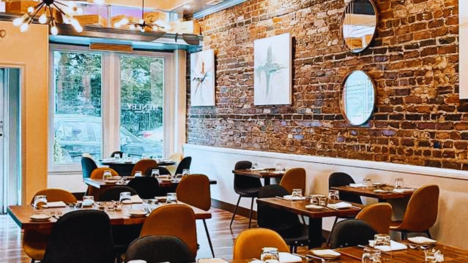 A cozy restaurant featuring exposed brick walls and wooden tables arranged for dining.