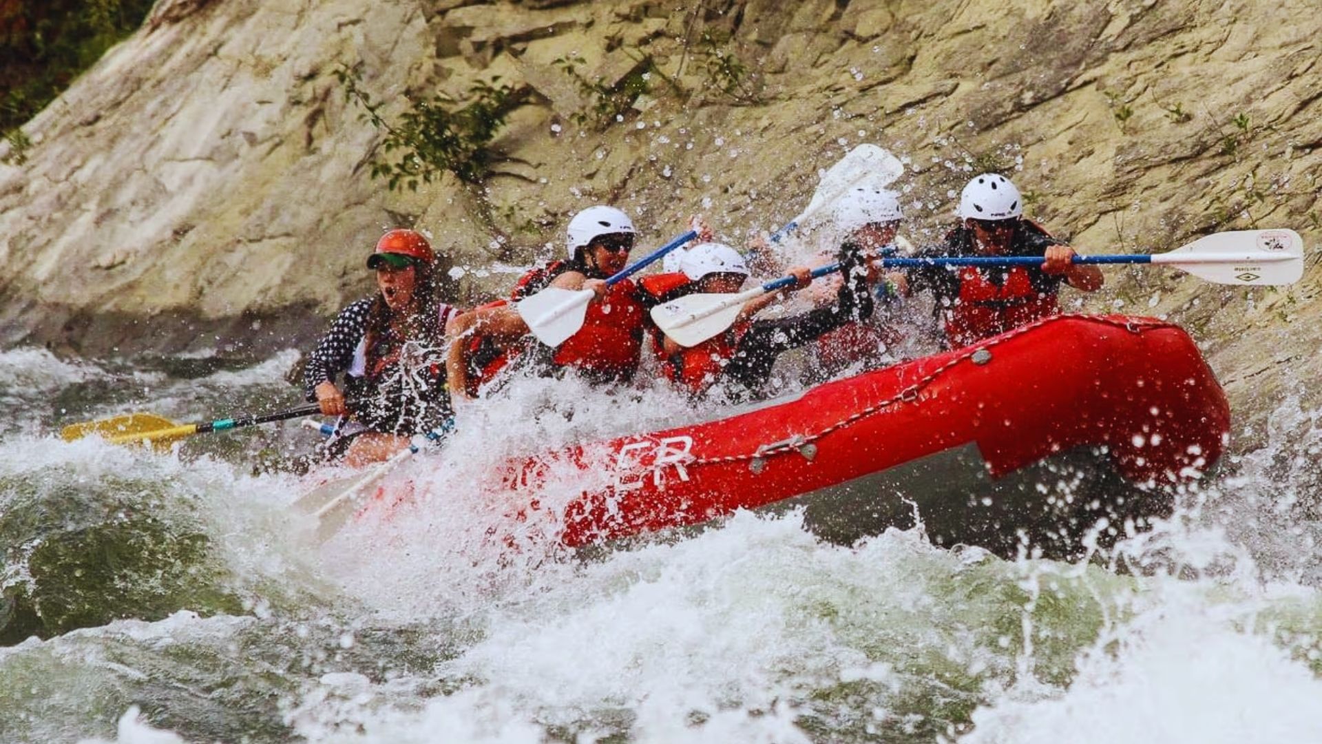 A group of people navigating a raft through turbulent rapids, showcasing excitement and teamwork in an outdoor adventure.