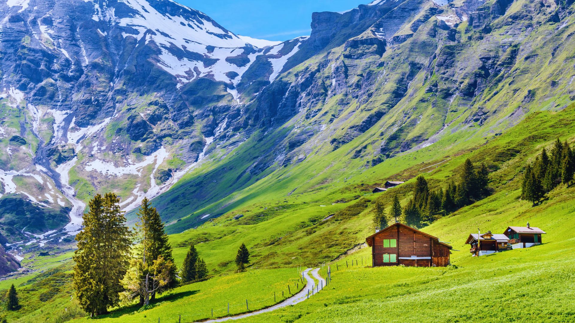 A small cabin nestled in the mountains, with a stunning mountain range visible in the background.