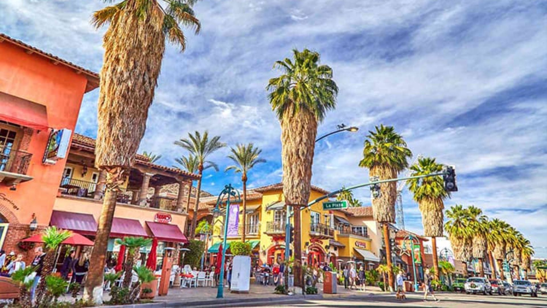 A vibrant street in Palm Springs lined with palm trees and colorful shops, showcasing the area's lively atmosphere.