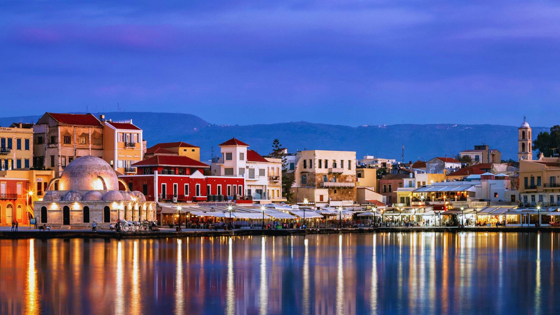 The city of Chania, Greece at dusk, highlighting the tranquil harbor and charming buildings bathed in evening light.