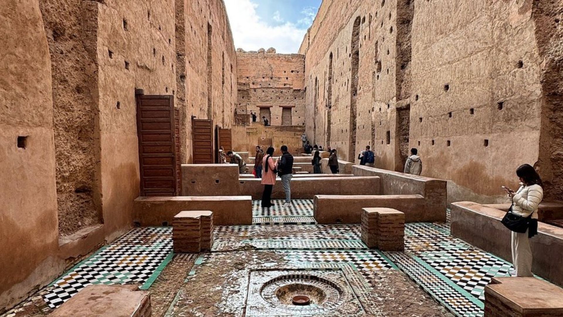 . A vibrant courtyard in the old city of Marrakech, featuring traditional architecture and lush greenery.