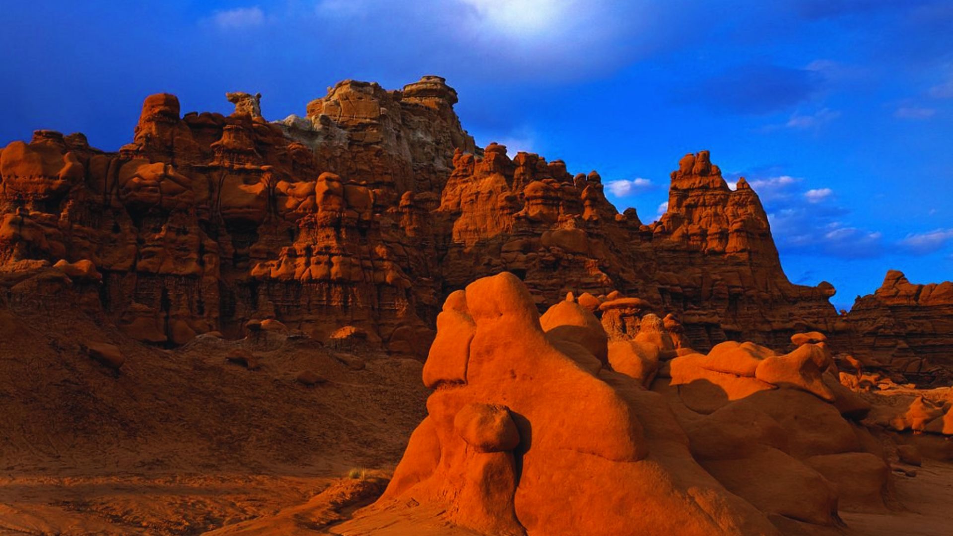 Sunlight illuminates a rugged rocky landscape, highlighting the textures and contours of the terrain.