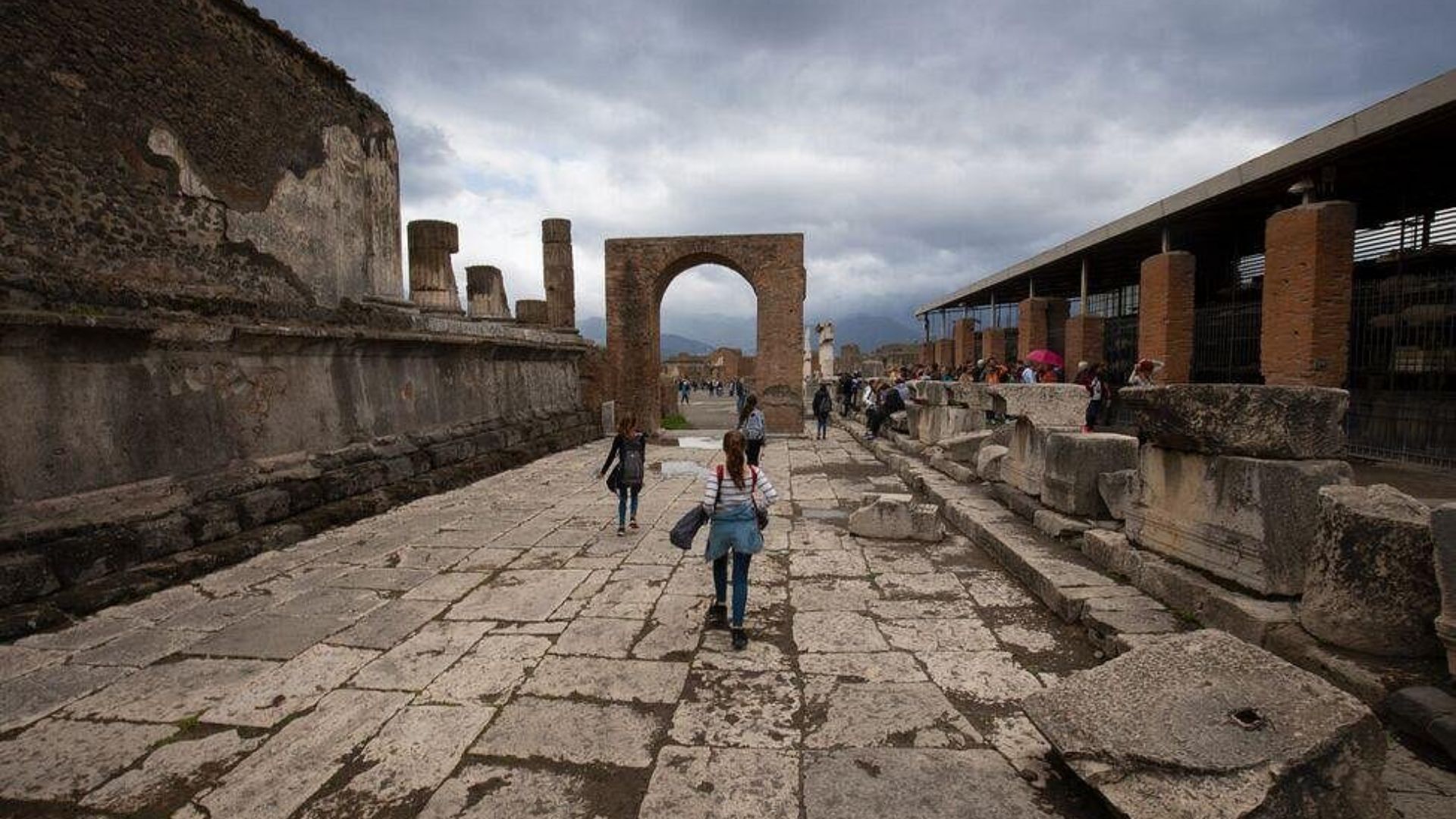A woman walks through the ancient ruins of Pompeii, Italy, on June 28, 2019, surrounded by historic stone structures.