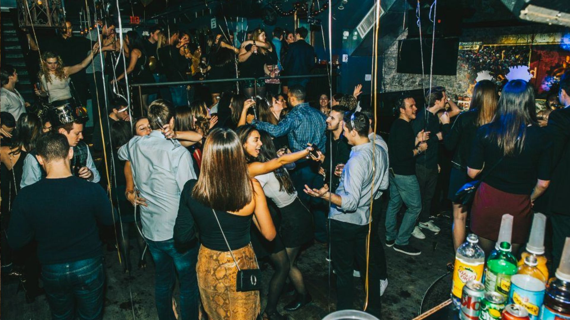 A lively nightclub scene filled with people dancing and enjoying drinks in a vibrant atmosphere.