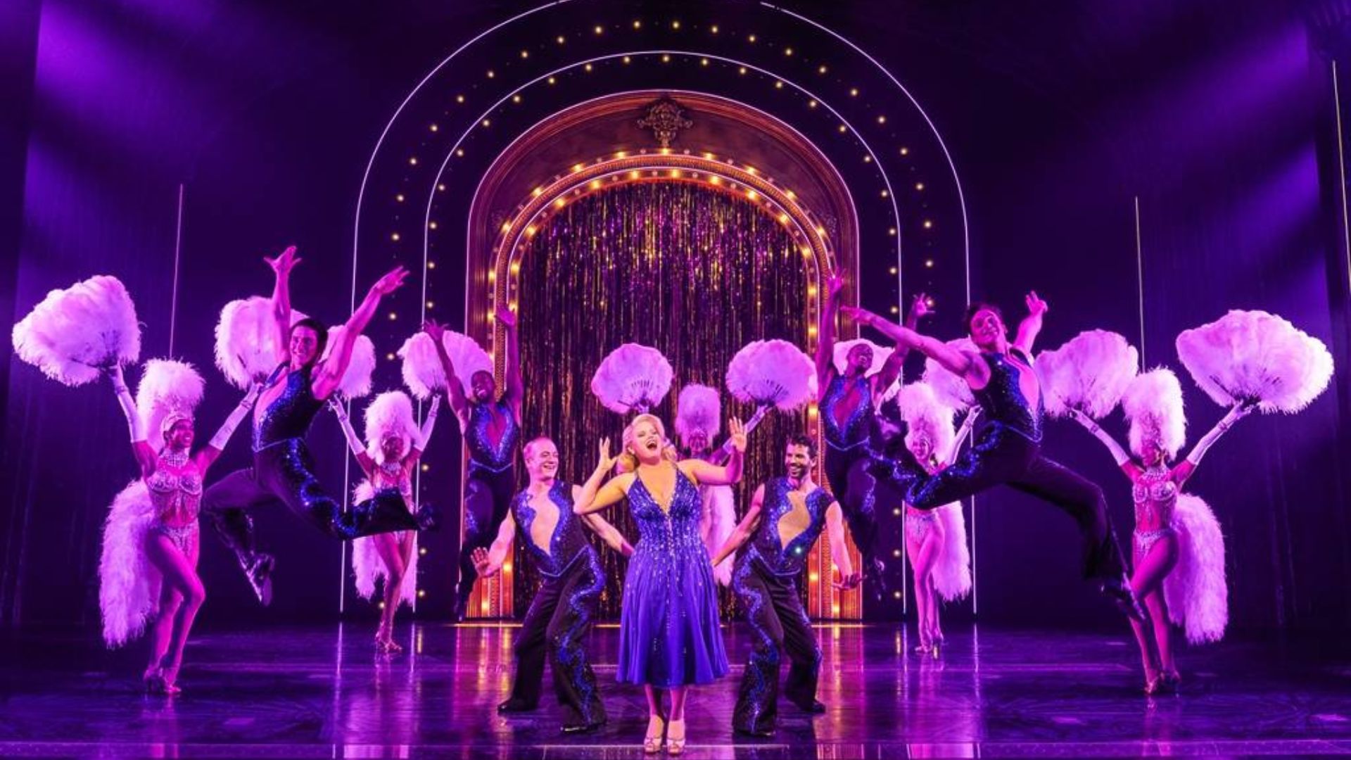 The ensemble cast of "Broadway Baby" stands together, radiating energy and excitement in their theatrical attire.