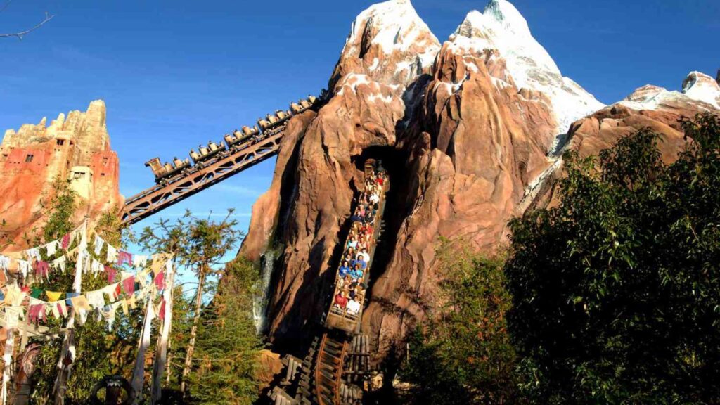 A mountain coaster with several people enjoying the ride, surrounded by scenic mountain views.