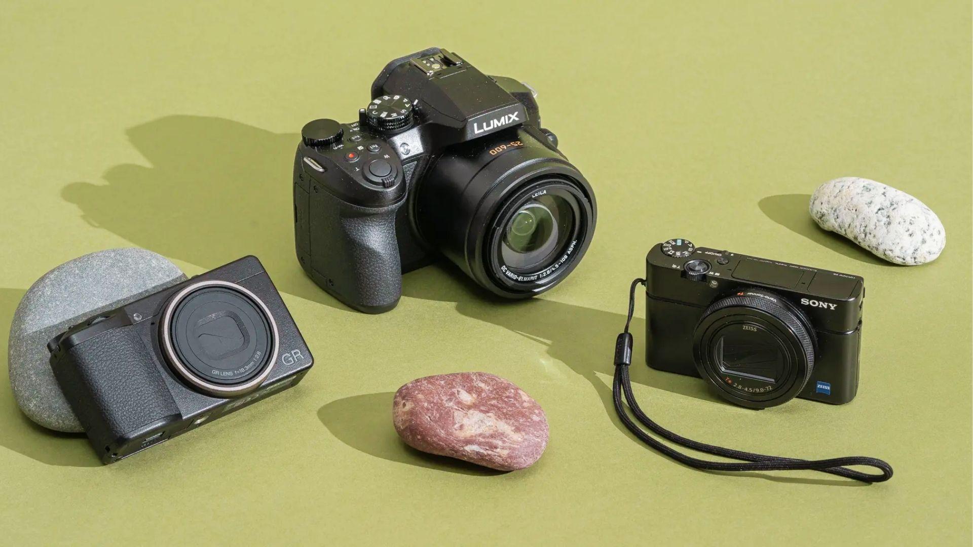 Flat lay of three travel cameras on sage green background