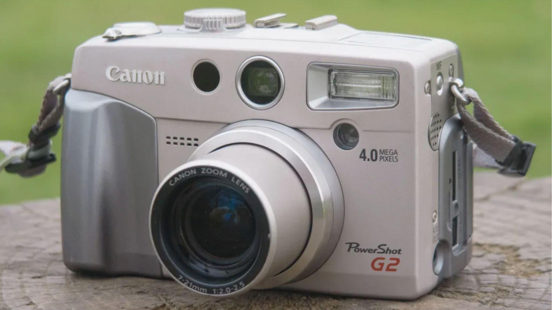 Silver Canon PowerShot G2 compact digital camera on a rustic wooden surface