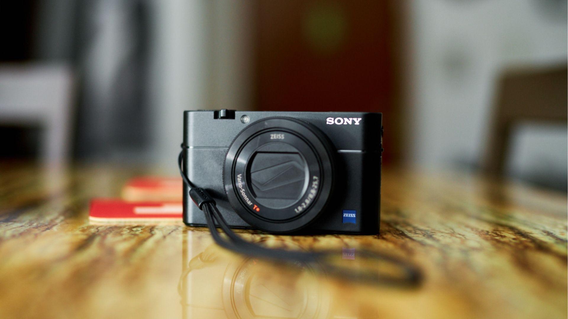 Sleek black Sony RX100 compact travel camera with Zeiss lens on glossy wooden table