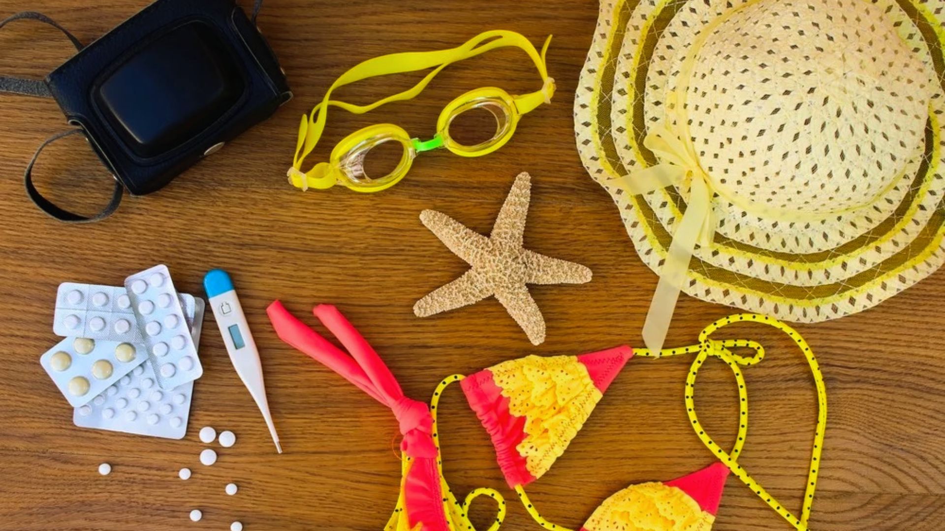 A collection of summer accessories, including sunglasses and a hat, arranged on a rustic wooden table.