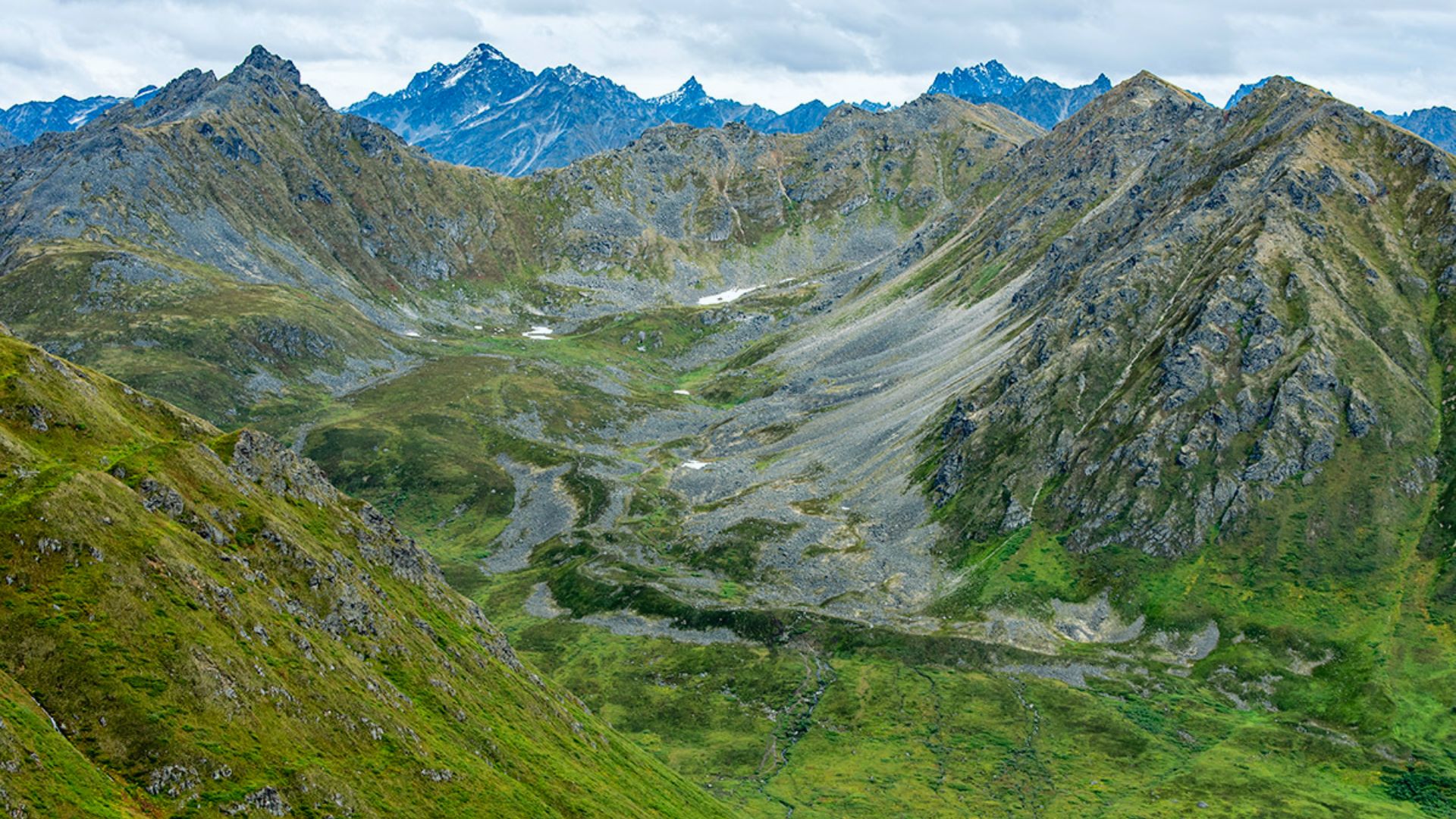 Aerial view of majestic mountains, showcasing peaks and valleys under a clear blue sky.
