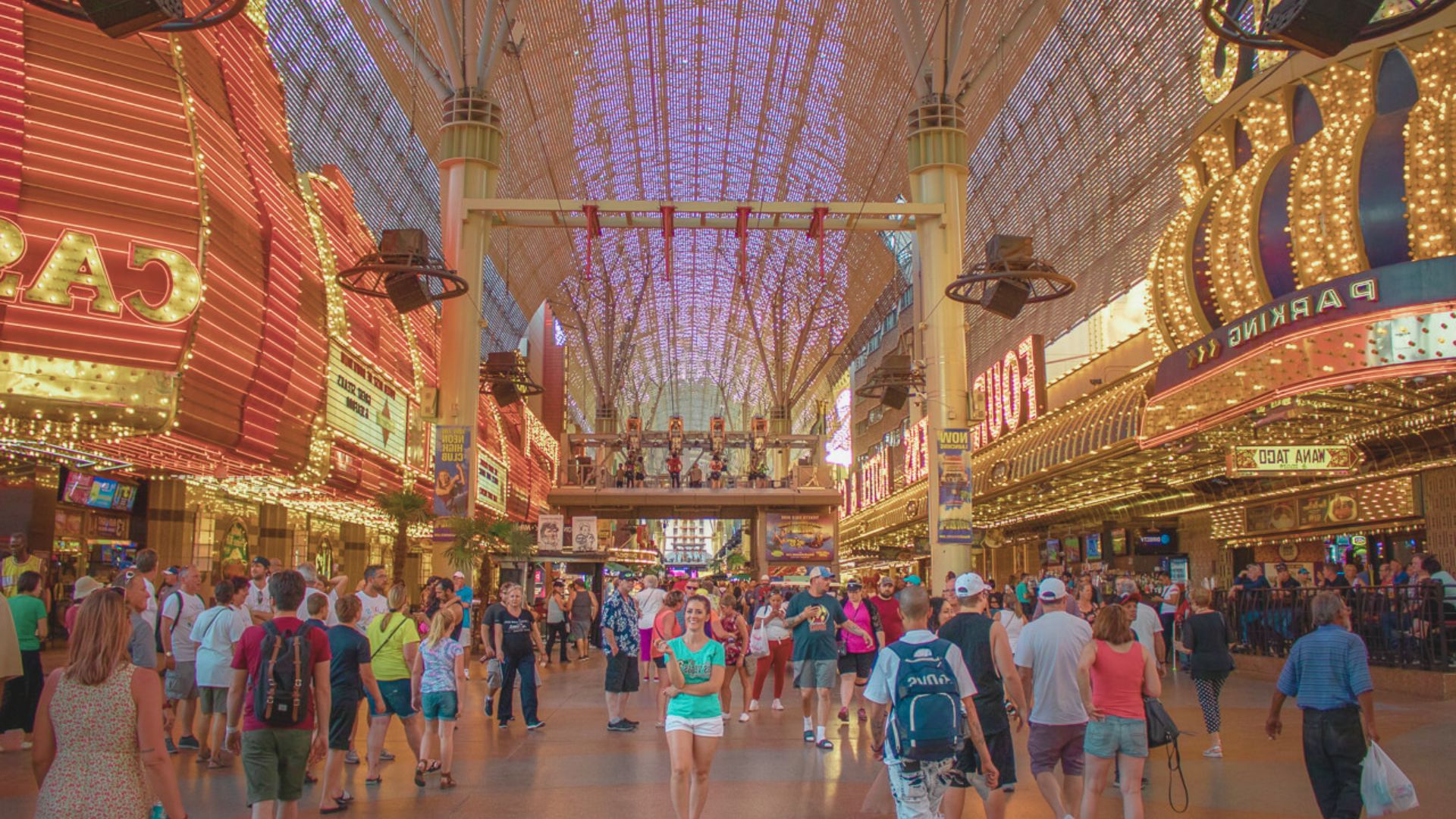 A bustling shopping mall interior filled with people walking and browsing various stores.