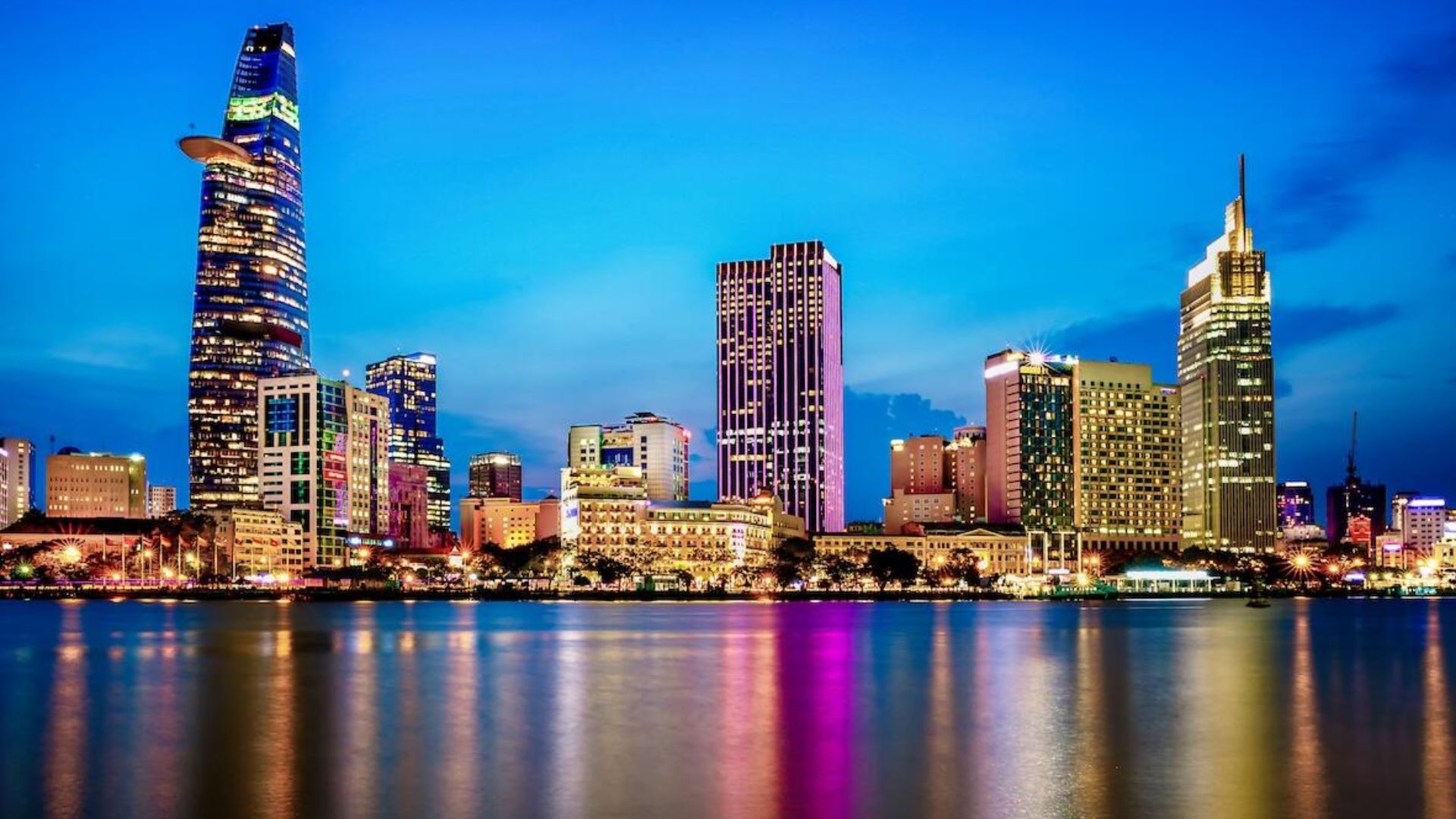 Ho Chi Minh City skyline illuminated at night, showcasing tall buildings and vibrant city lights against a dark sky.