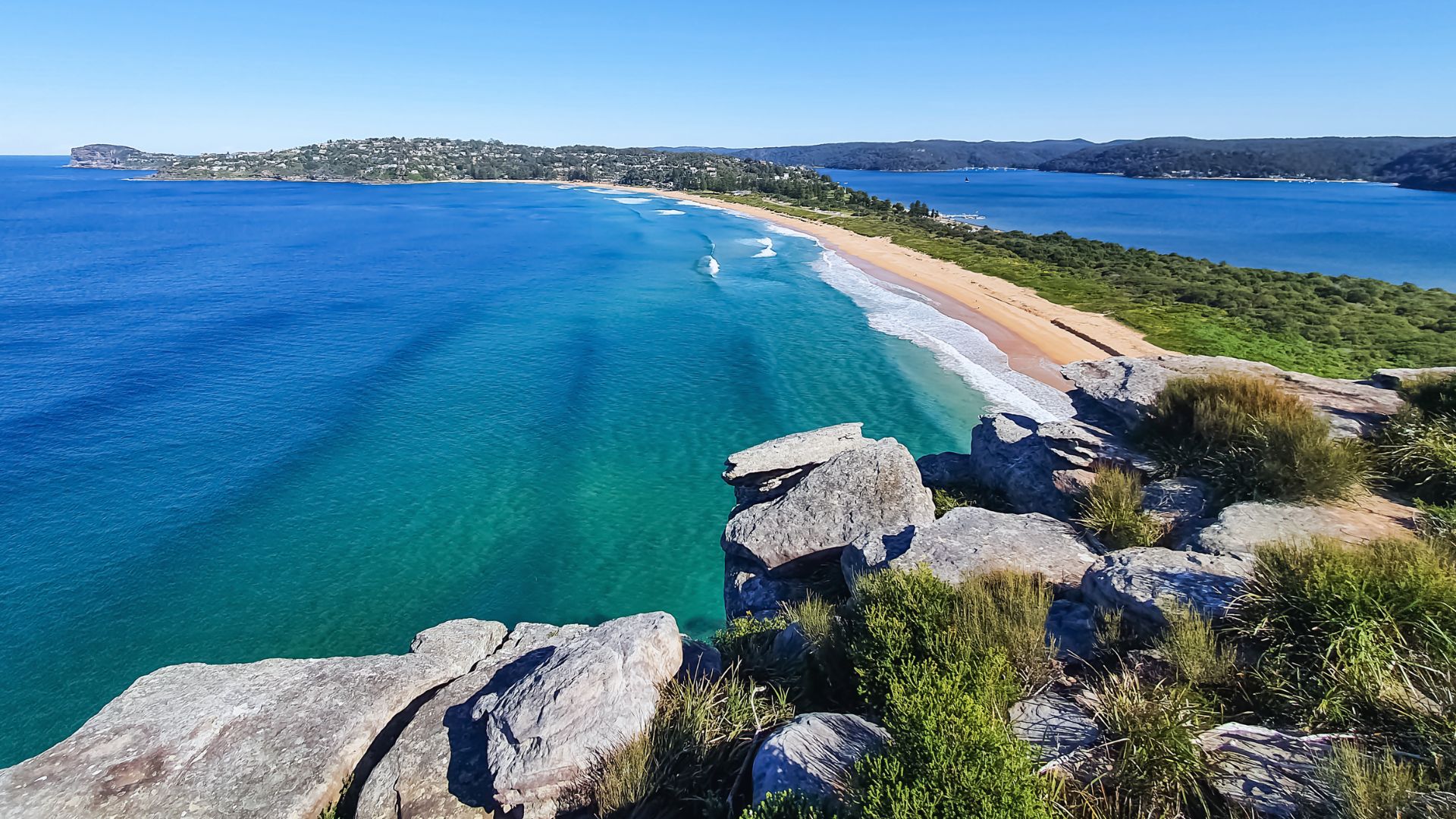A panoramic view from a cliff edge, showcasing the vast ocean stretching to the horizon under a clear blue sky.