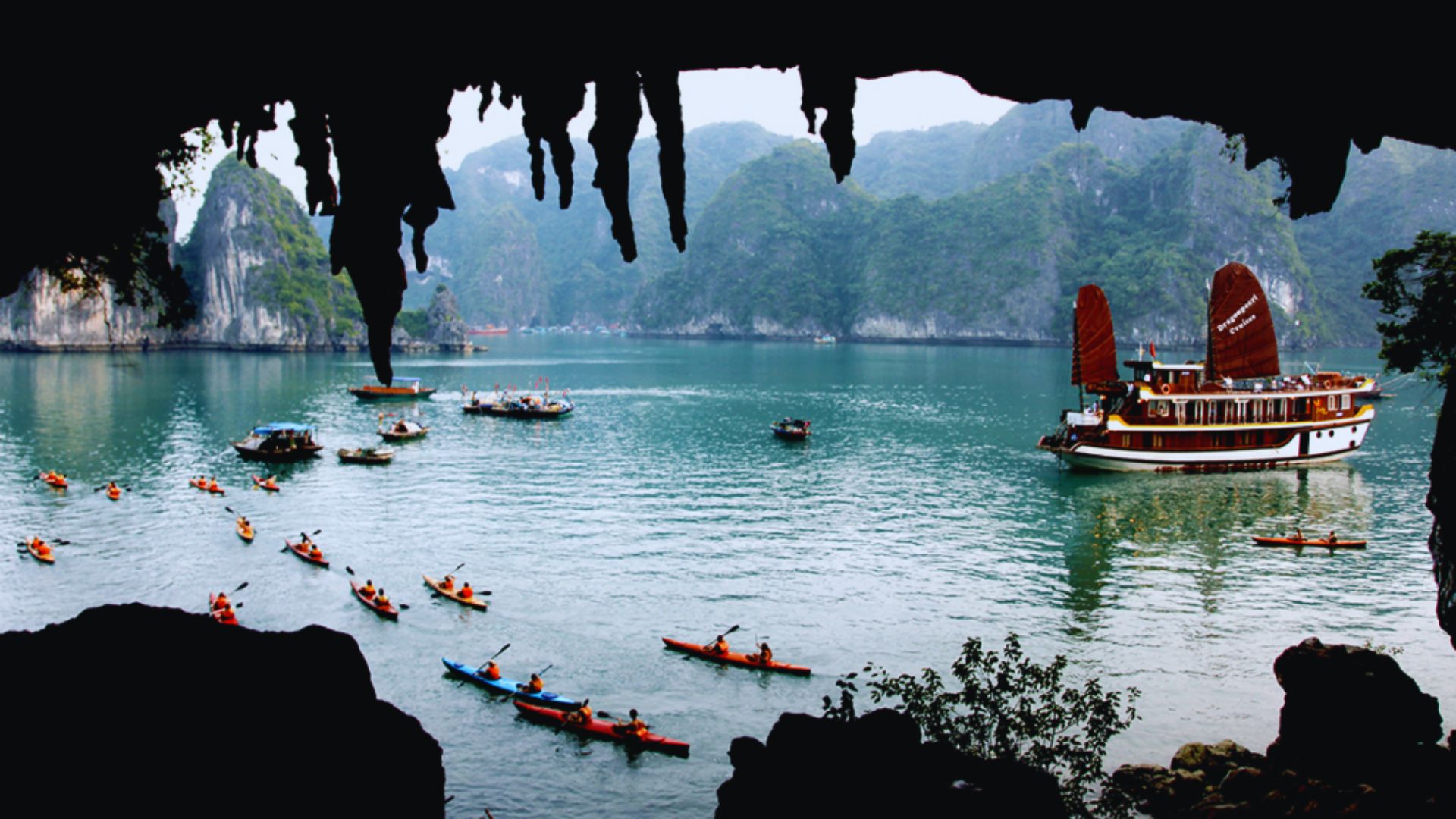 A boat floats on the water with a large rock formation visible in the background.