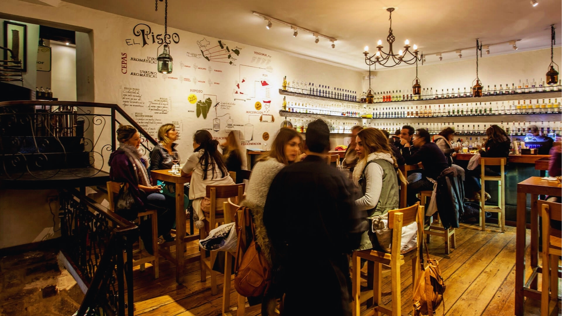 A group of people dining at tables in a restaurant, engaged in conversation and enjoying their meals.