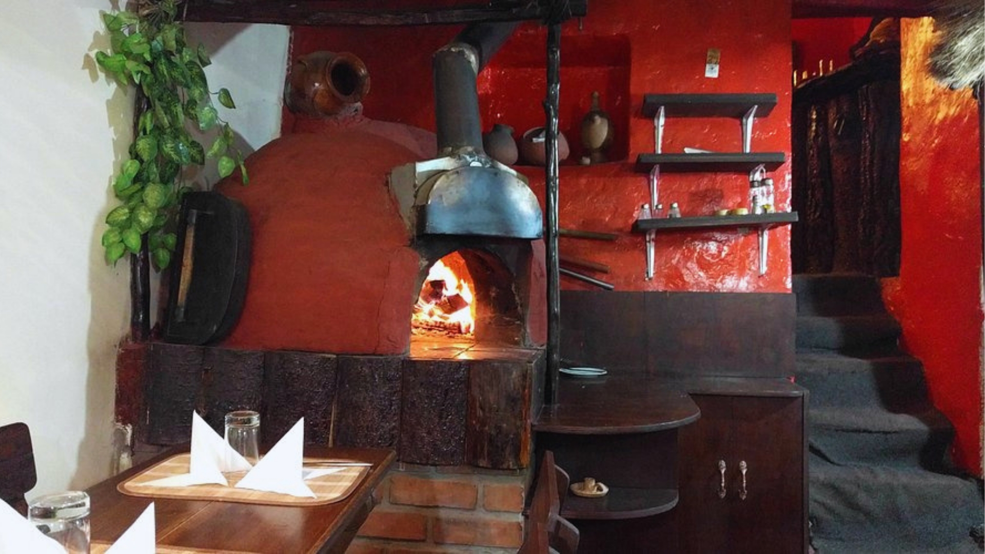 A cozy restaurant featuring a wood-burning oven and a neatly set dining table.