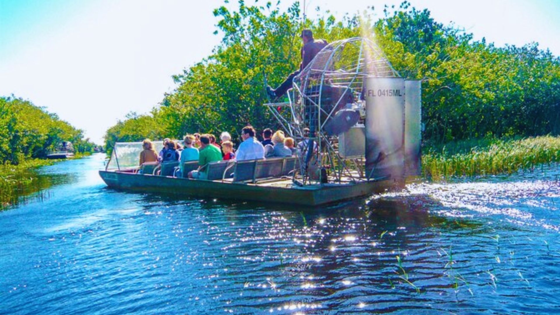 A group of people enjoying a ride on an airboat as it glides through the water.