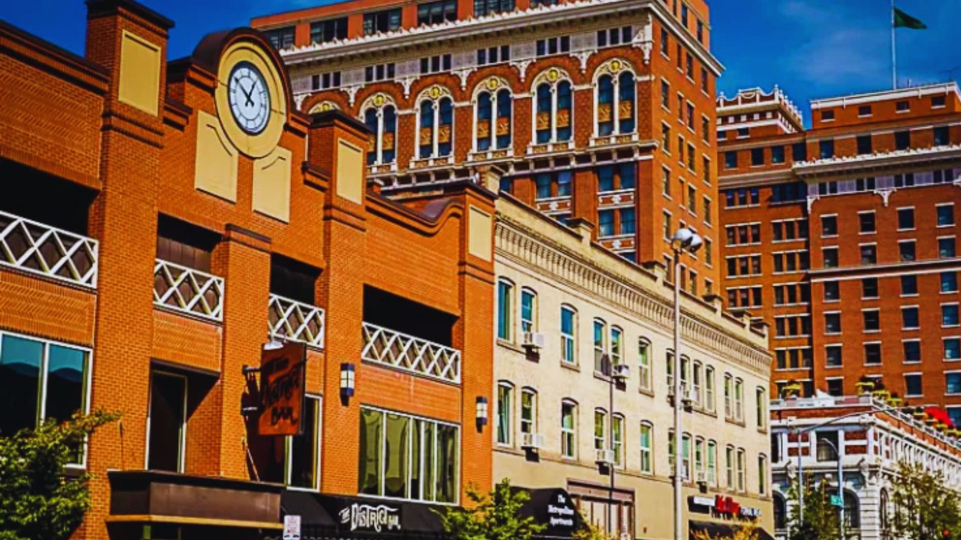 A city street featuring tall buildings and a prominent clock mounted on a wall.