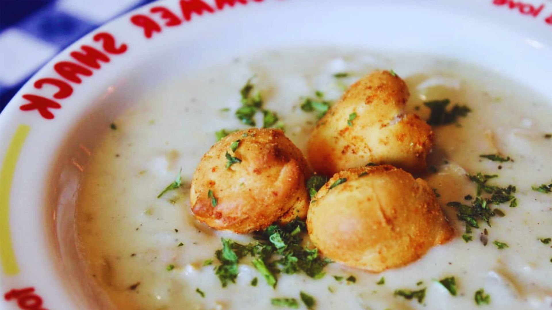 A bowl of soup accompanied by a loaf of bread and two round bread rolls on a wooden table.
