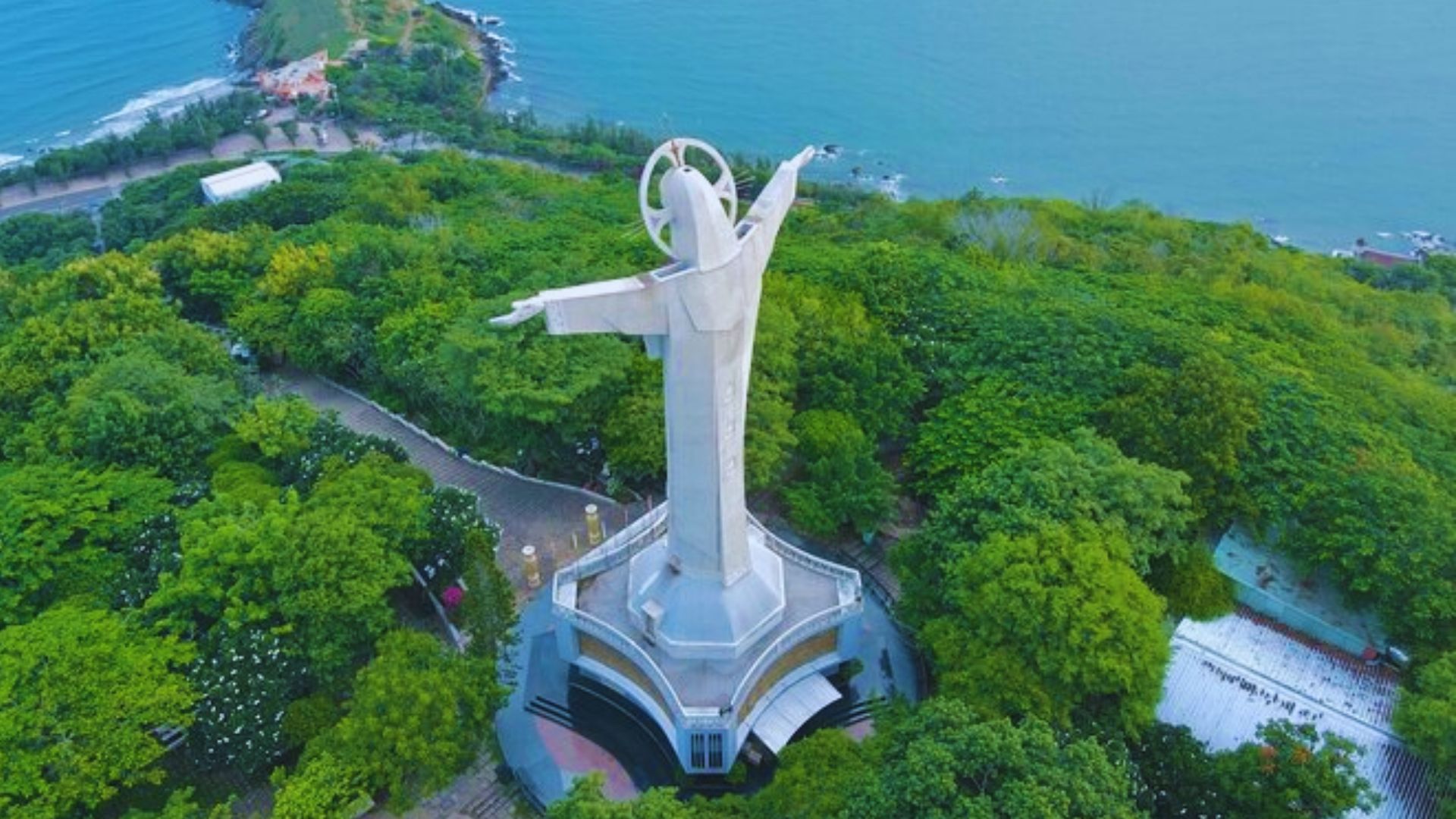 A statue of Christ stands majestically in the ocean, surrounded by water and a clear blue sky.