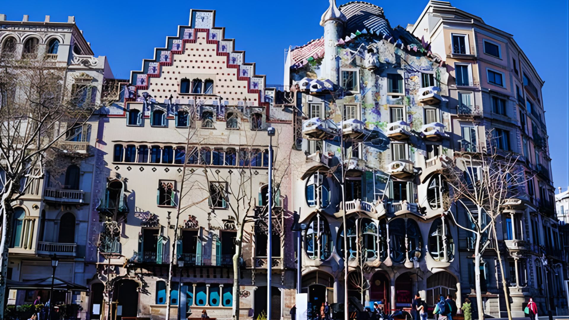 Colorful, uniquely designed buildings under a clear blue sky. Architectural elements include ornate facades and decorative balconies, creating an artistic and whimsical atmosphere.