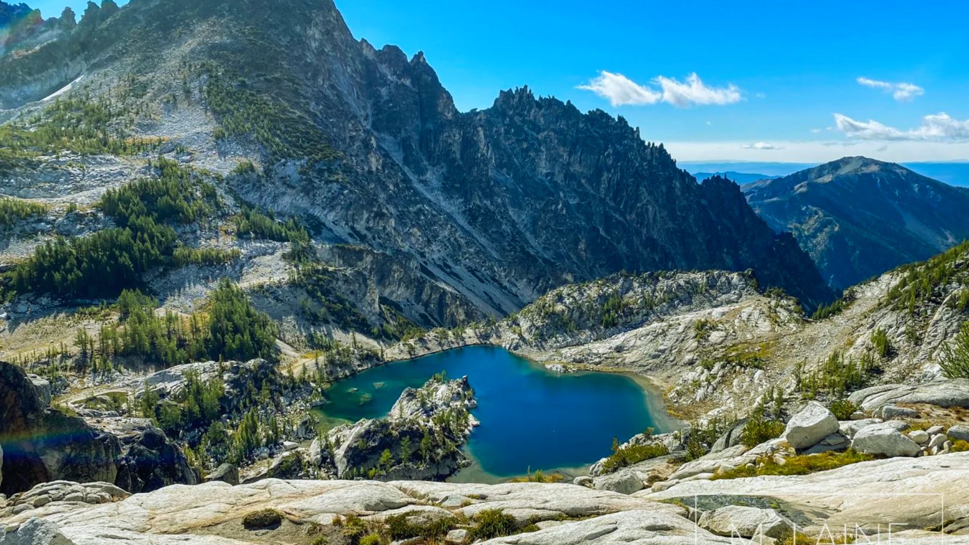 A serene lake surrounded by mountains, with a majestic mountain range visible in the background.