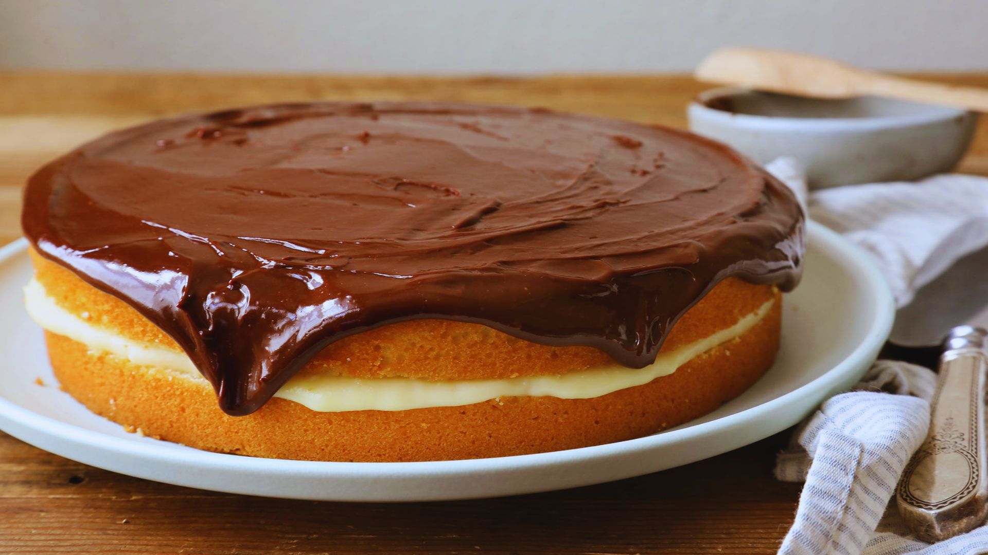 A chocolate frosted cake displayed on a white plate, showcasing its rich texture and smooth icing.