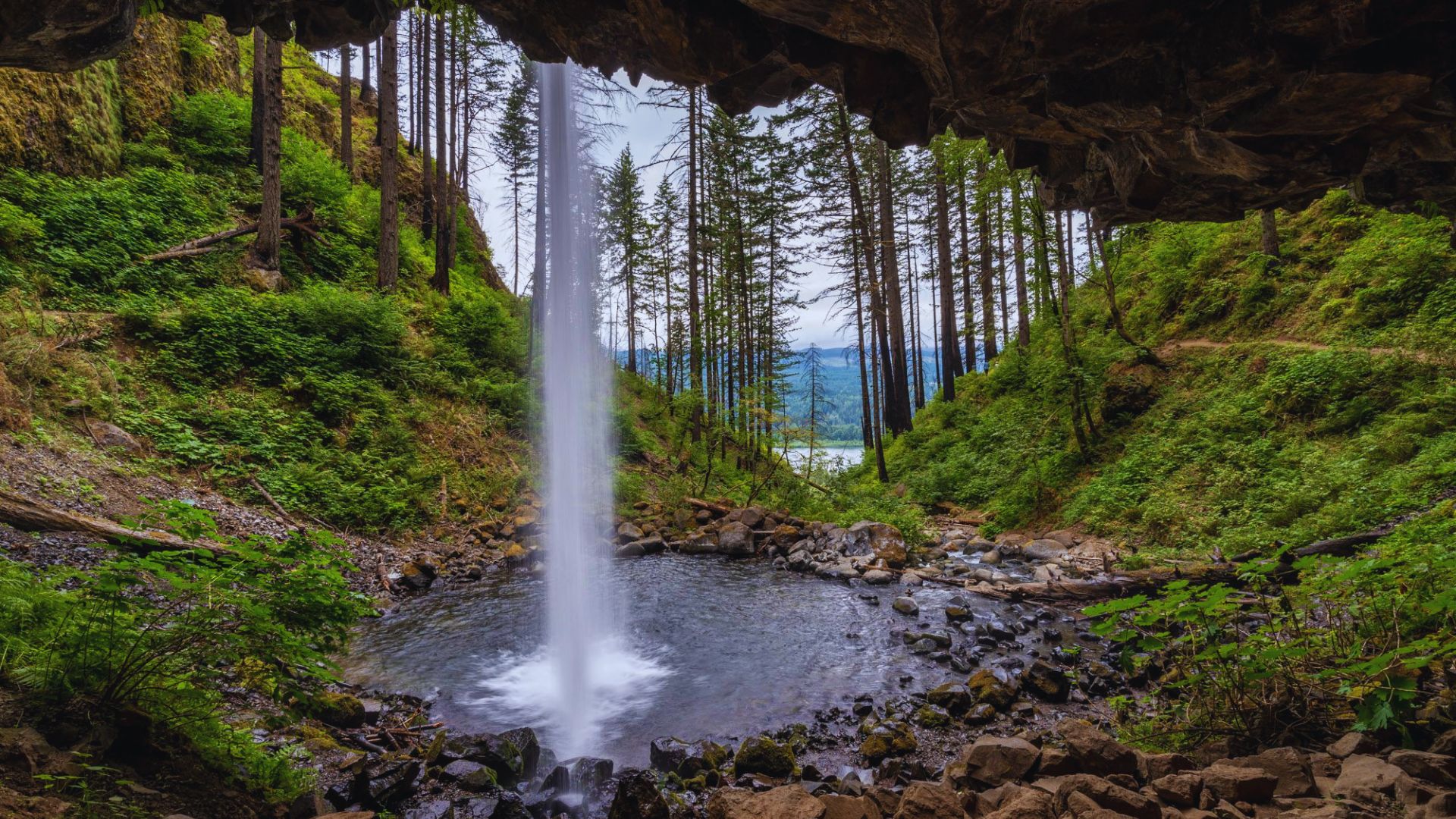 A serene waterfall cascading inside a dark cave, surrounded by rocky walls and illuminated by soft, natural light.