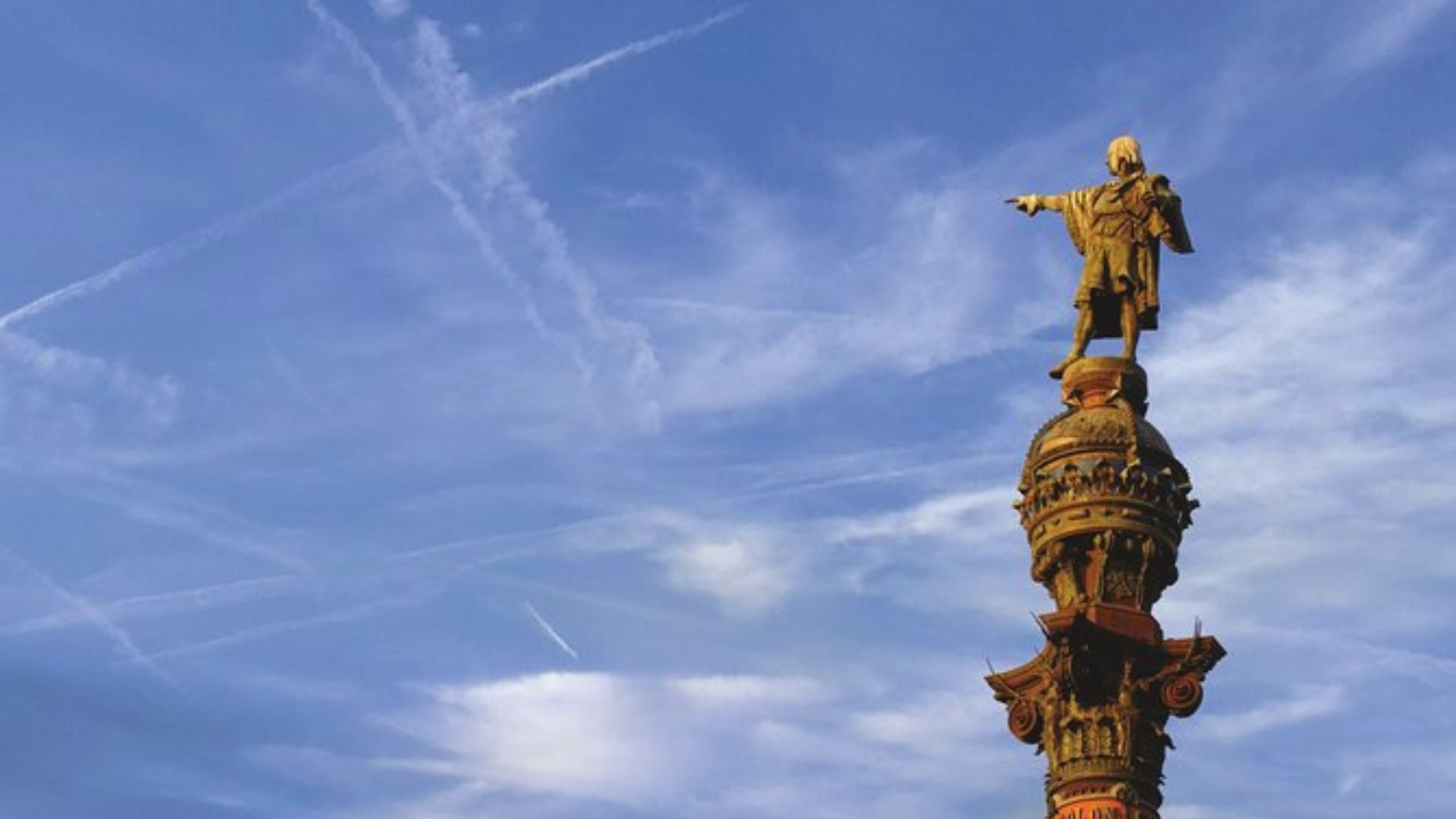 Statue atop an ornate column with a figure pointing outward against a blue sky crisscrossed with vapor trails. The scene conveys a sense of exploration.