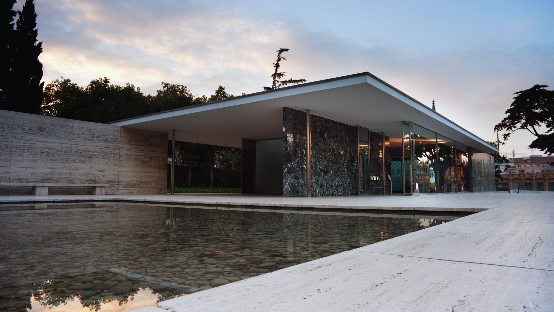 Modernist pavilion with flat roof and glass walls, showcasing marble panels. A calm reflecting pool in front, surrounded by minimalist landscaping at dusk.