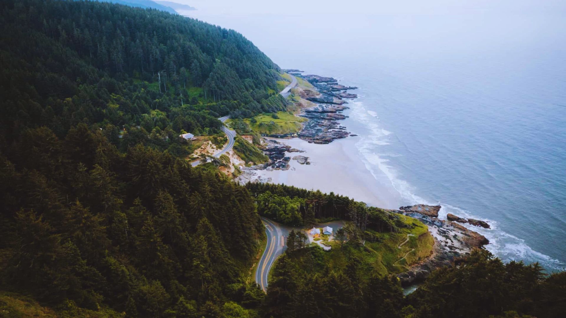 A panoramic view from a cliff's edge, showcasing the vast ocean stretching to the horizon under a clear blue sky.