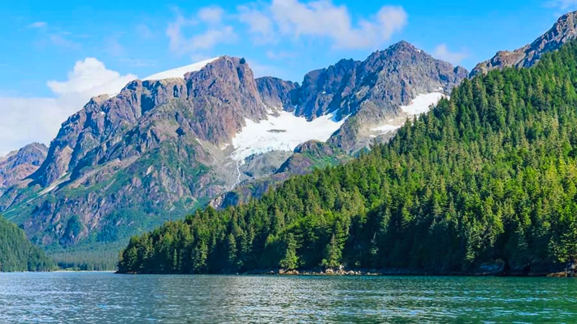Scenic view of mountains and trees reflected on calm water under a clear sky.