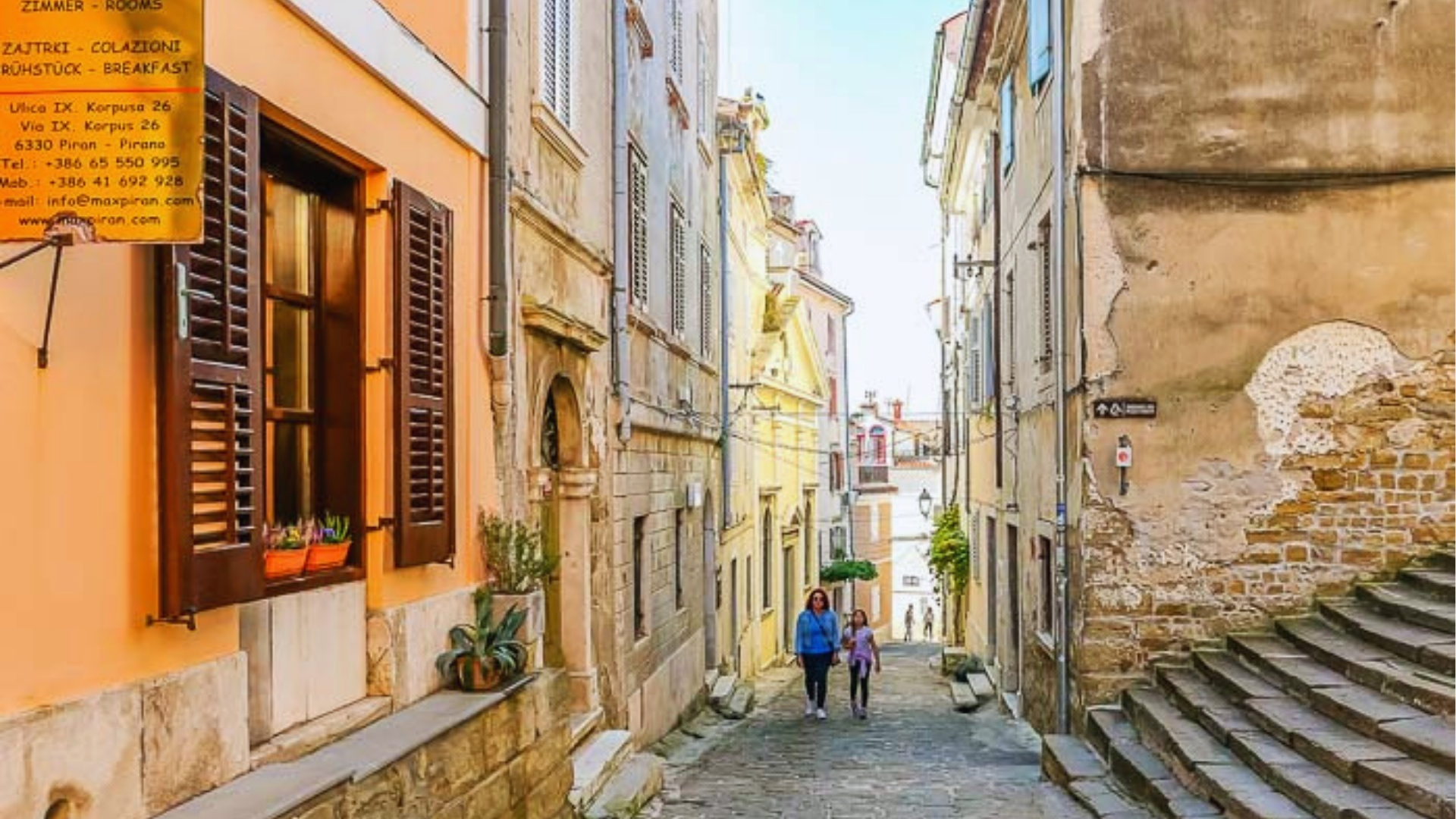 A narrow street featuring steps that ascend to a building, framed by surrounding architecture.