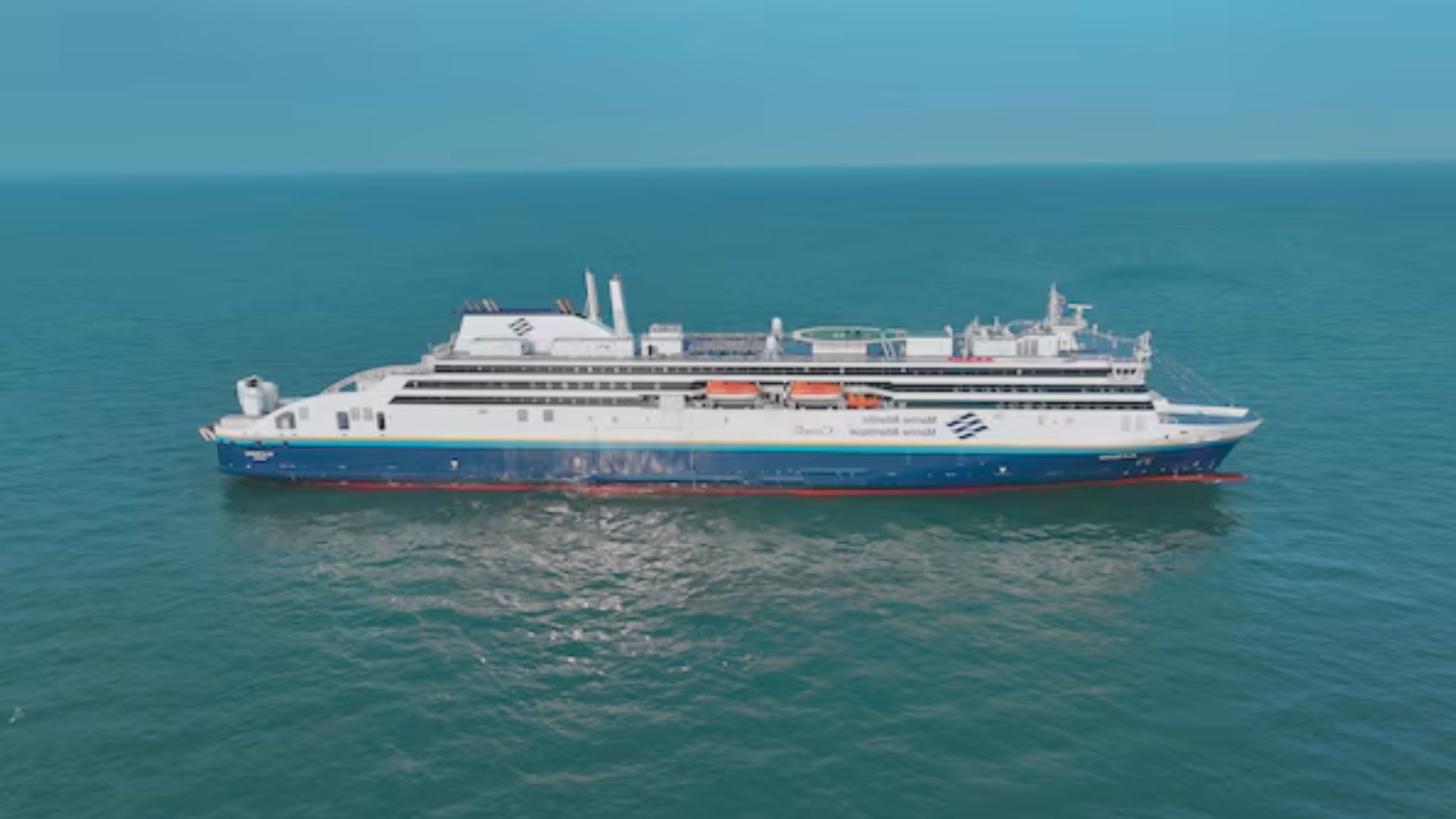 A large ferry boat sailing across the ocean under a clear blue sky.