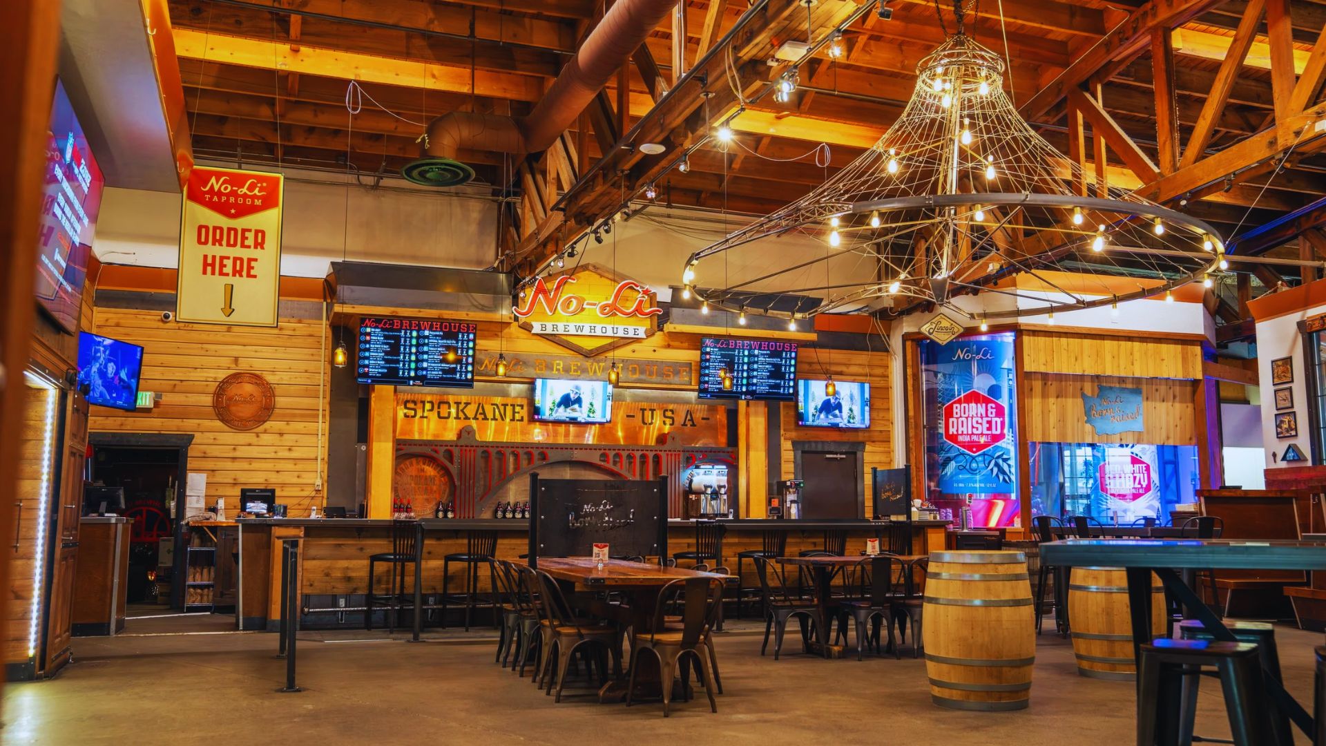 A lively bar featuring a large screen and numerous tables for patrons to enjoy food and drinks.