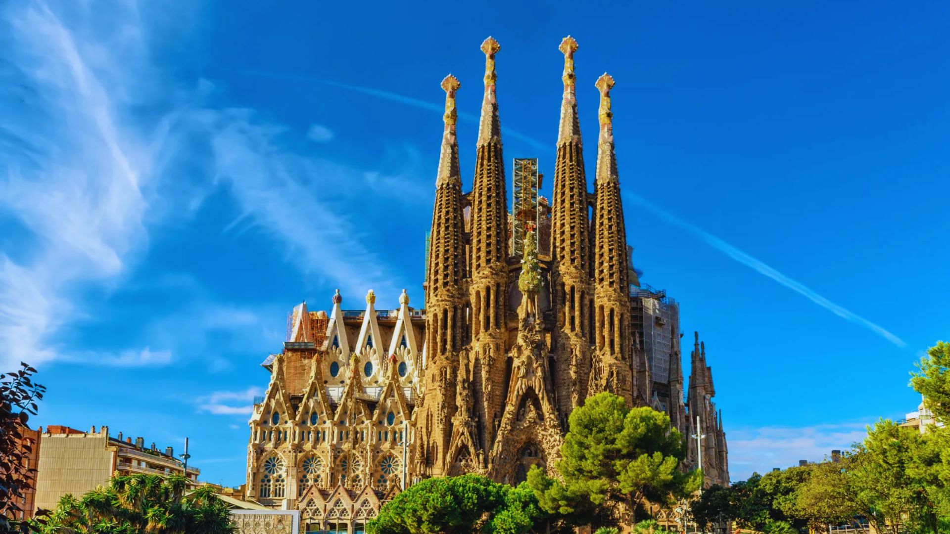 A stunning view of the Sagrada Familia in Barcelona against a vibrant blue sky. The intricate spires and gothic architecture create a majestic presence.