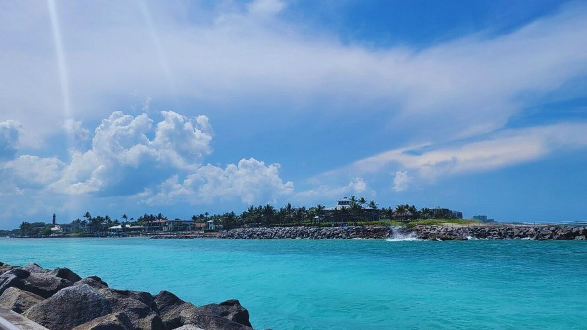 A serene beach scene at the end of a road, with gentle waves lapping at the shore under a clear blue sky.