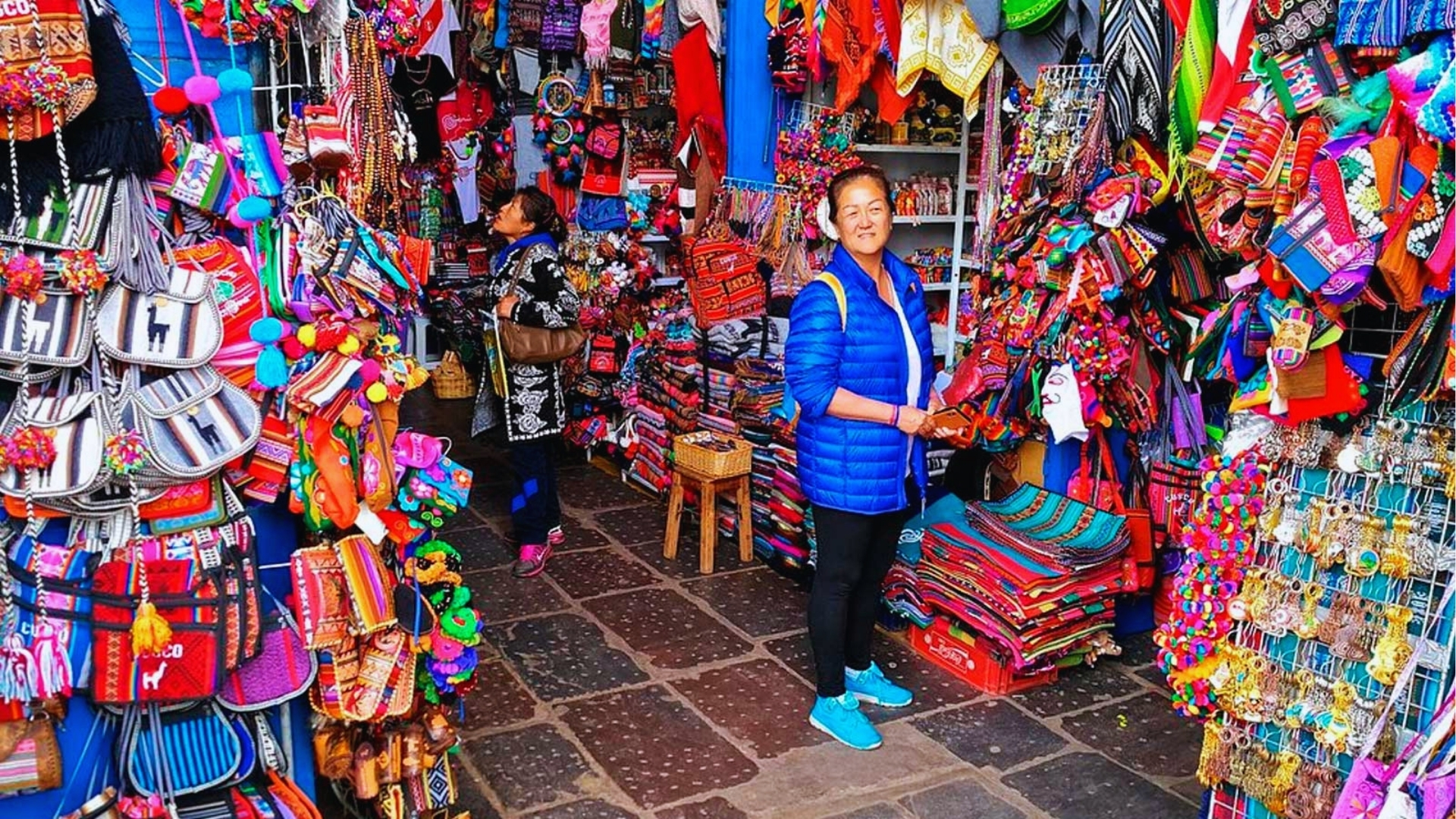 A woman stands in a vibrant market filled with a variety of colorful items and goods.