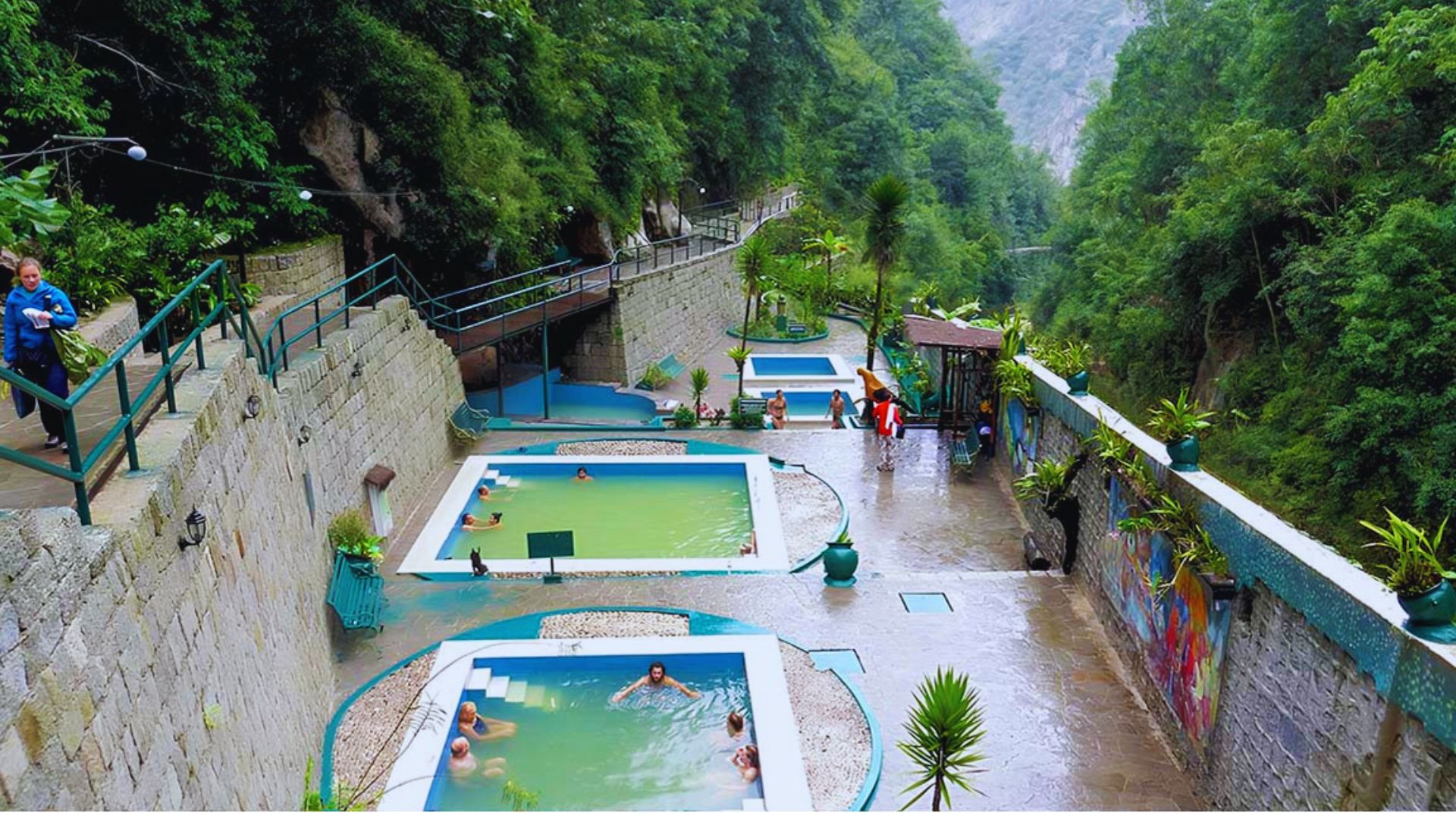 A serene pool nestled among lush green mountains under a clear blue sky.