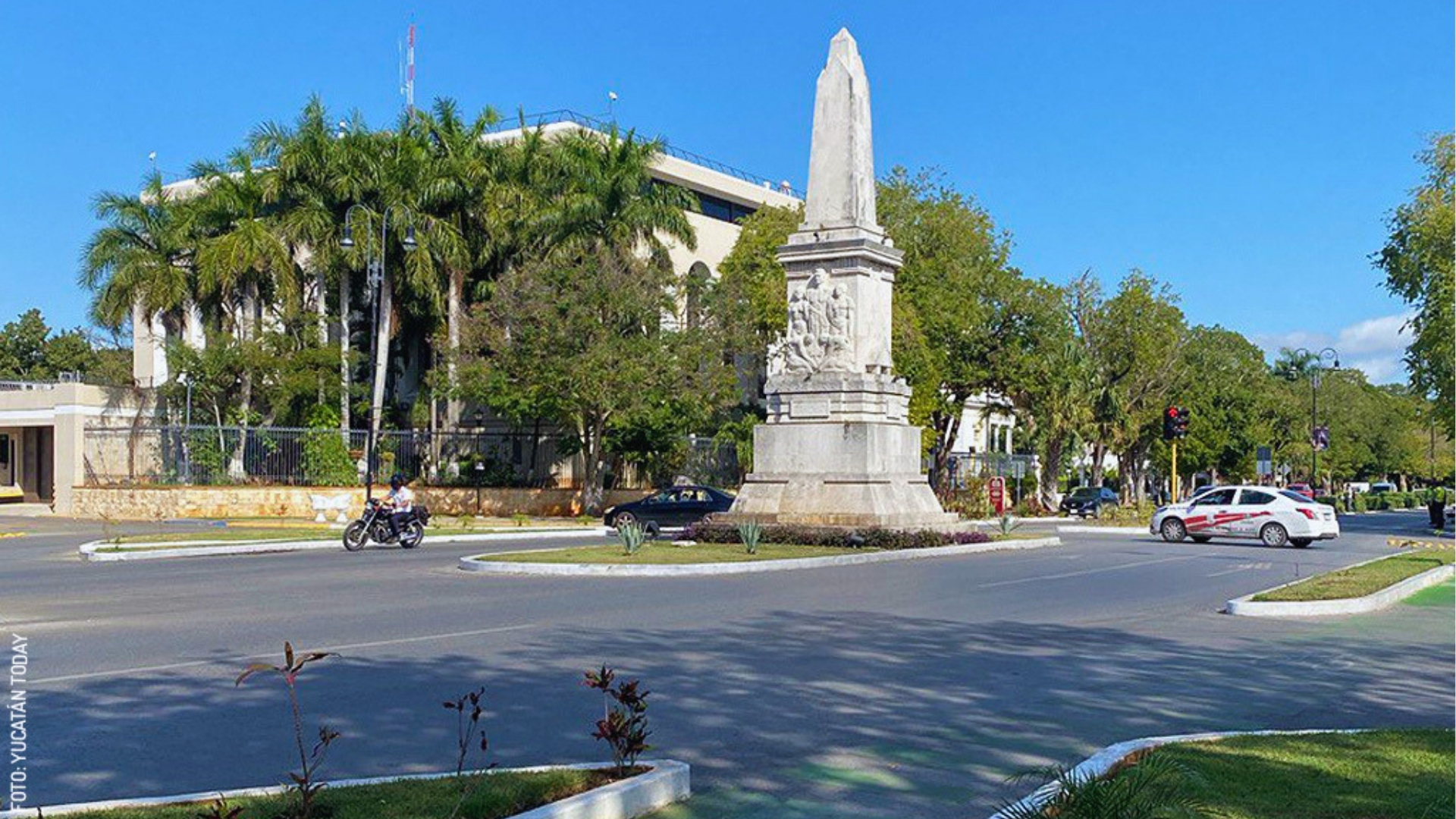 A street monument stands prominently as a car drives past, highlighting the urban landscape and traffic flow.