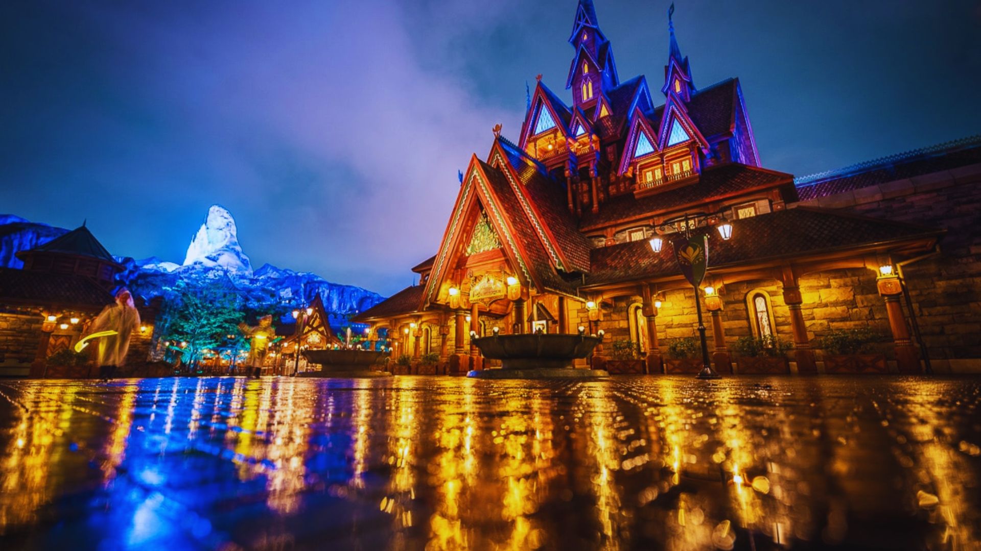 A castle illuminated at night, with its reflection shimmering in the calm water below.