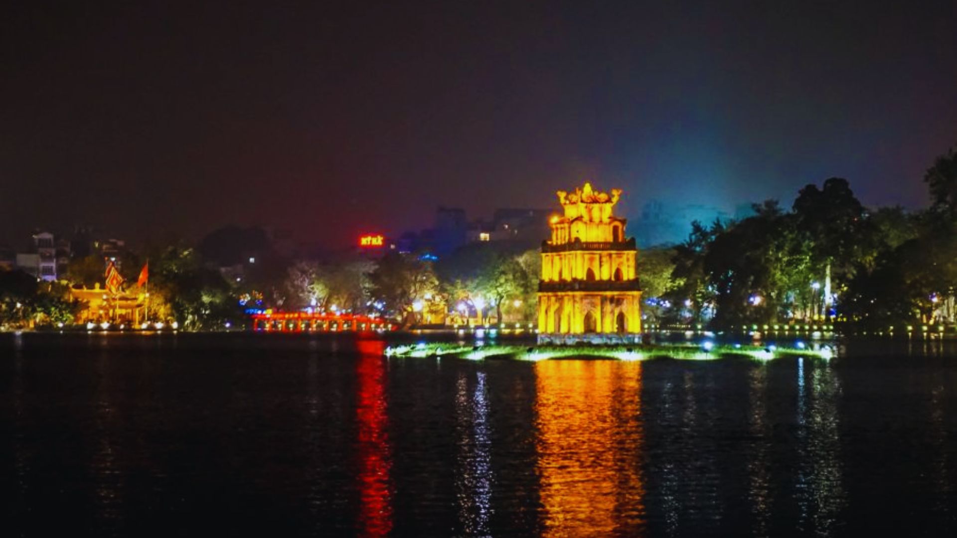Scenic view of Hoan Kiem Lake in Hanoi, Vietnam, surrounded by lush greenery and traditional architecture.