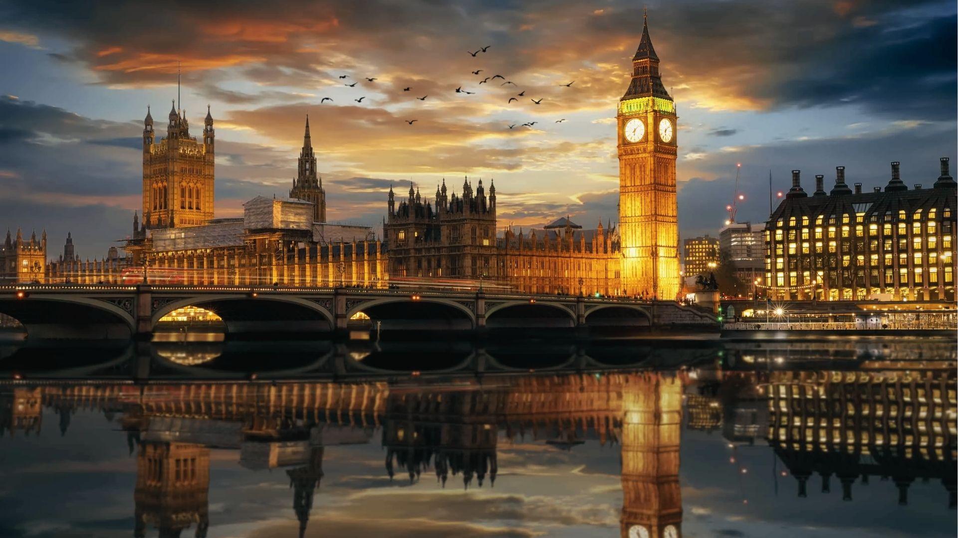 Big Ben and Parliament glow gold at sunset on the Thames. Iconic December lights in London.
