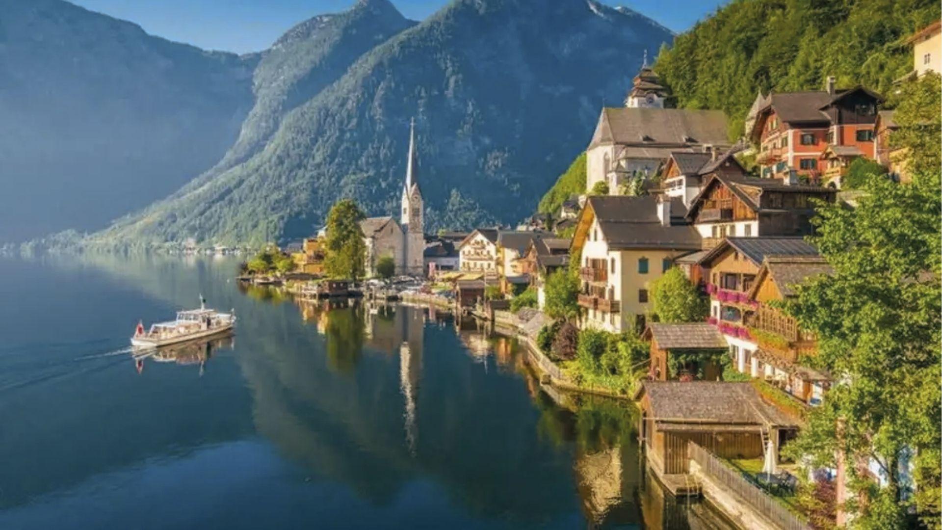 Lakeside village clings to steep Alps, church spires rise over boats in Austria’s fairytale gem.