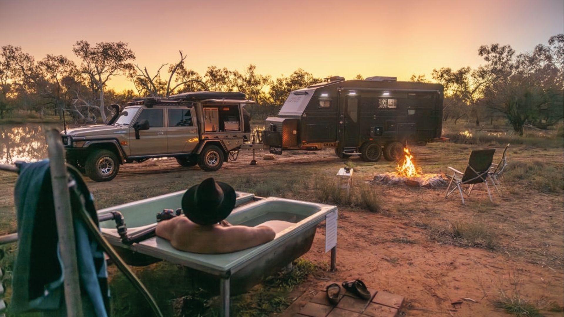 Camp by a river at dusk with a 4WD and fire, soak in an outdoor bath under outback stars.