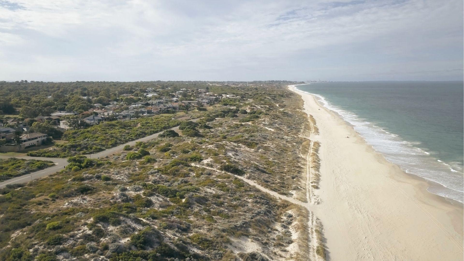 View a long sandy beach with coastal dunes from above, enjoy Perth’s quiet shoreline walks.