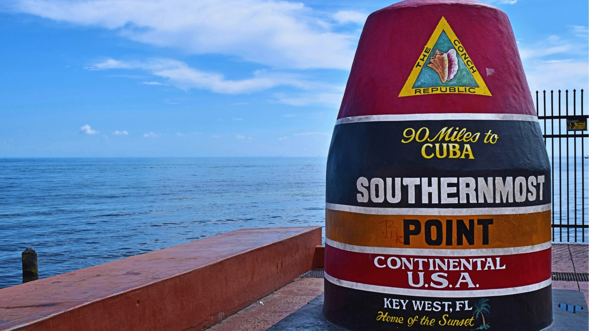 Colorful Southernmost Point buoy landmark reading 90 Miles to Cuba with ocean view in Key West Florida.