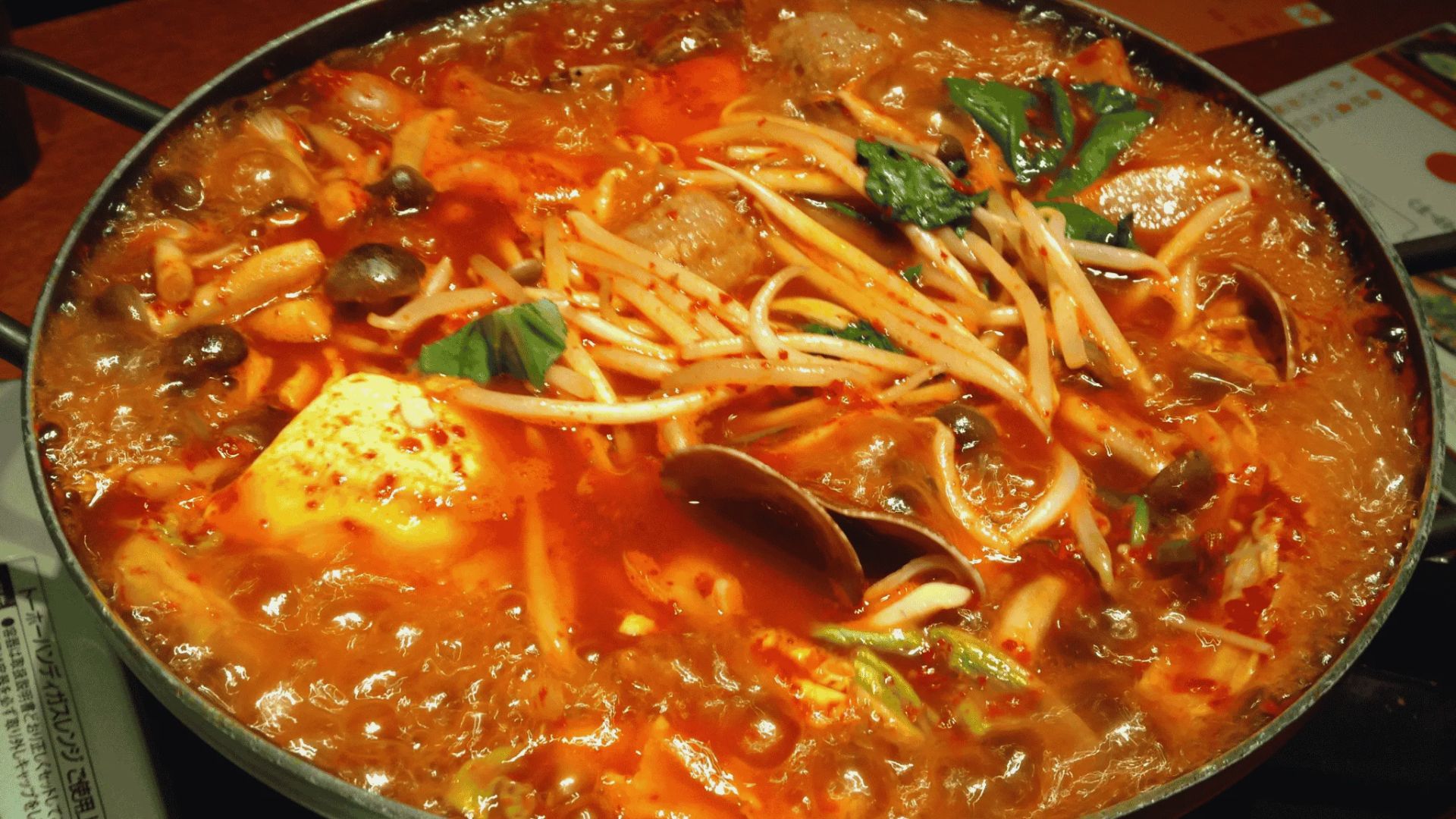 A bowl of soup filled with noodles and colorful vegetables, steaming and ready to be enjoyed.